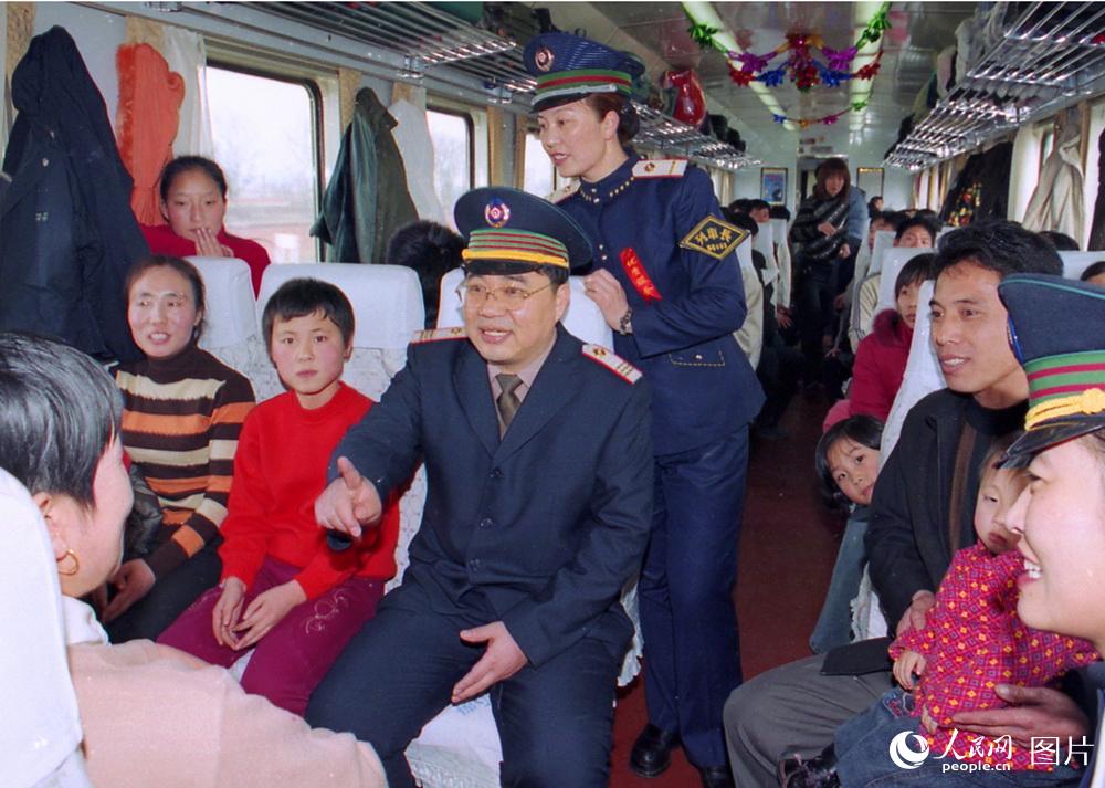 2005年春运第一天锦州客运段段长邢振国（中）。在开往北京的2590次列车上与旅客亲切交谈。高锦旭摄