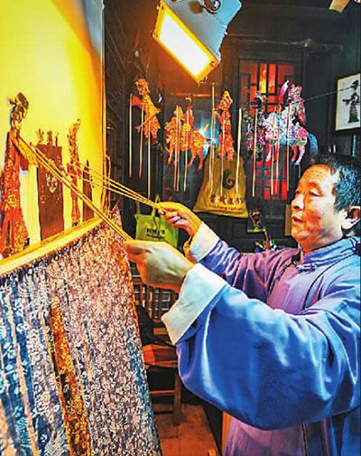 山东台儿庄古城非遗文化展示区，现年60岁的国家级非物质文化遗产鲁南皮影戏传承人陈守科正在向游客表演皮影戏，让游客们感受传统文化的魅力。高启民摄
